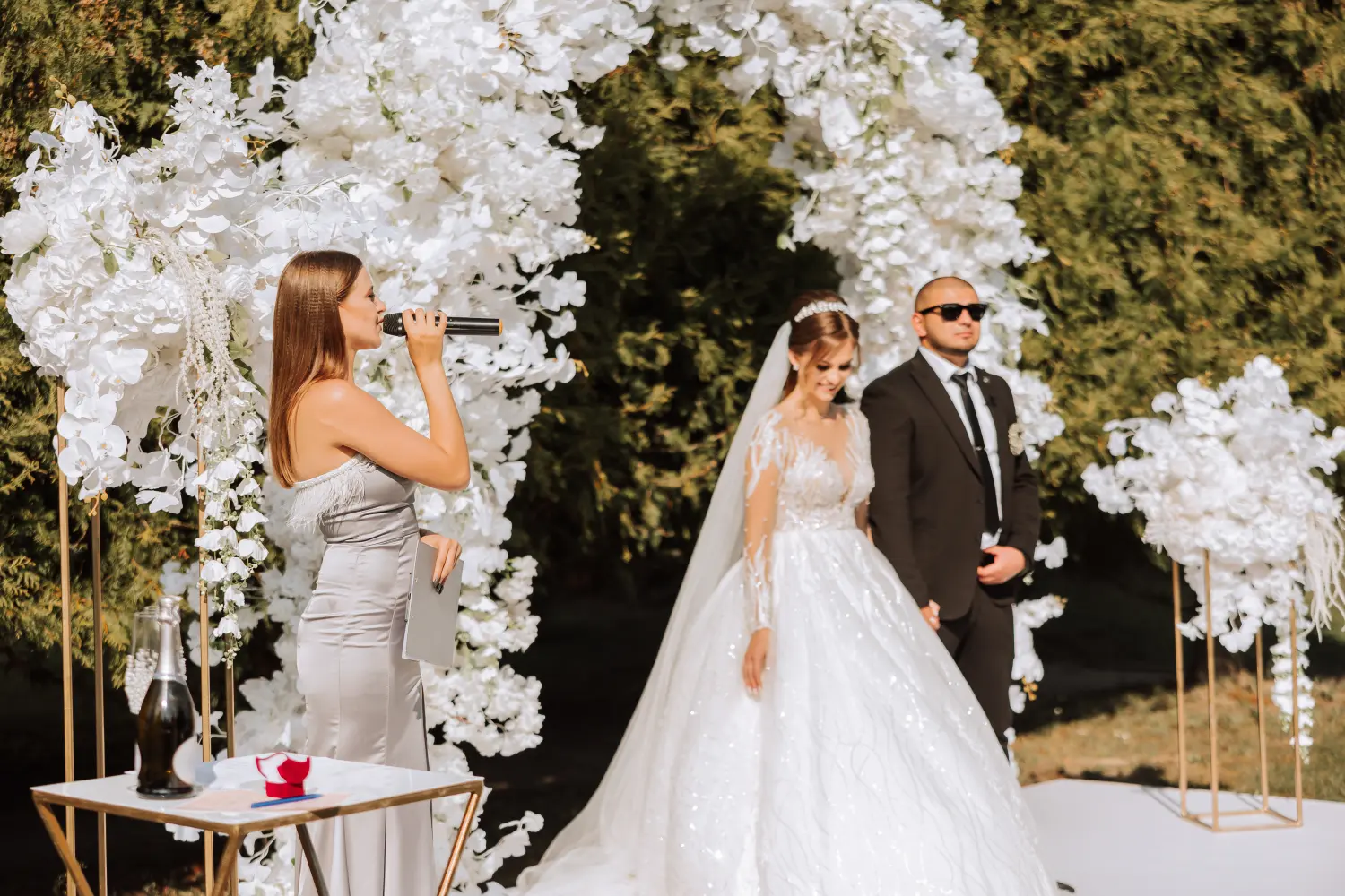 Eine Hochzeitsmoderatorin hält eine Rede und das Brautpaar